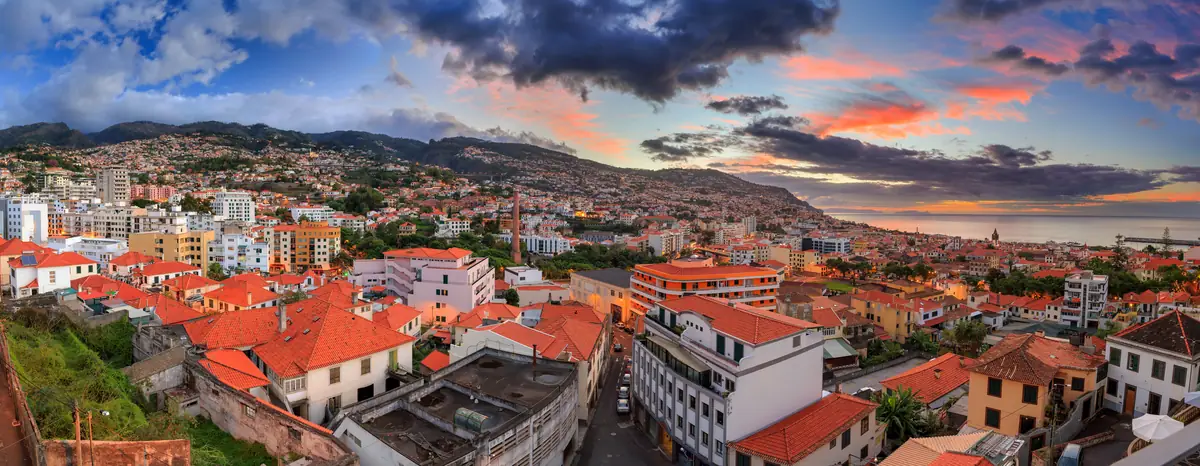 Panorama do Funchal ao amanhecer, com os telhados vermelhos e a baía